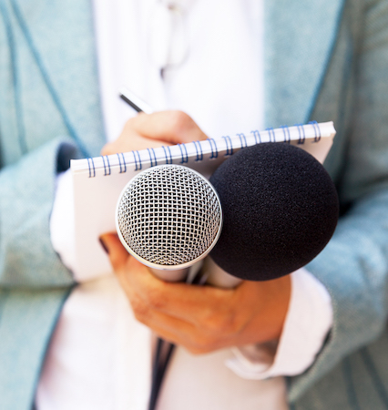hands holding microphones and notepad